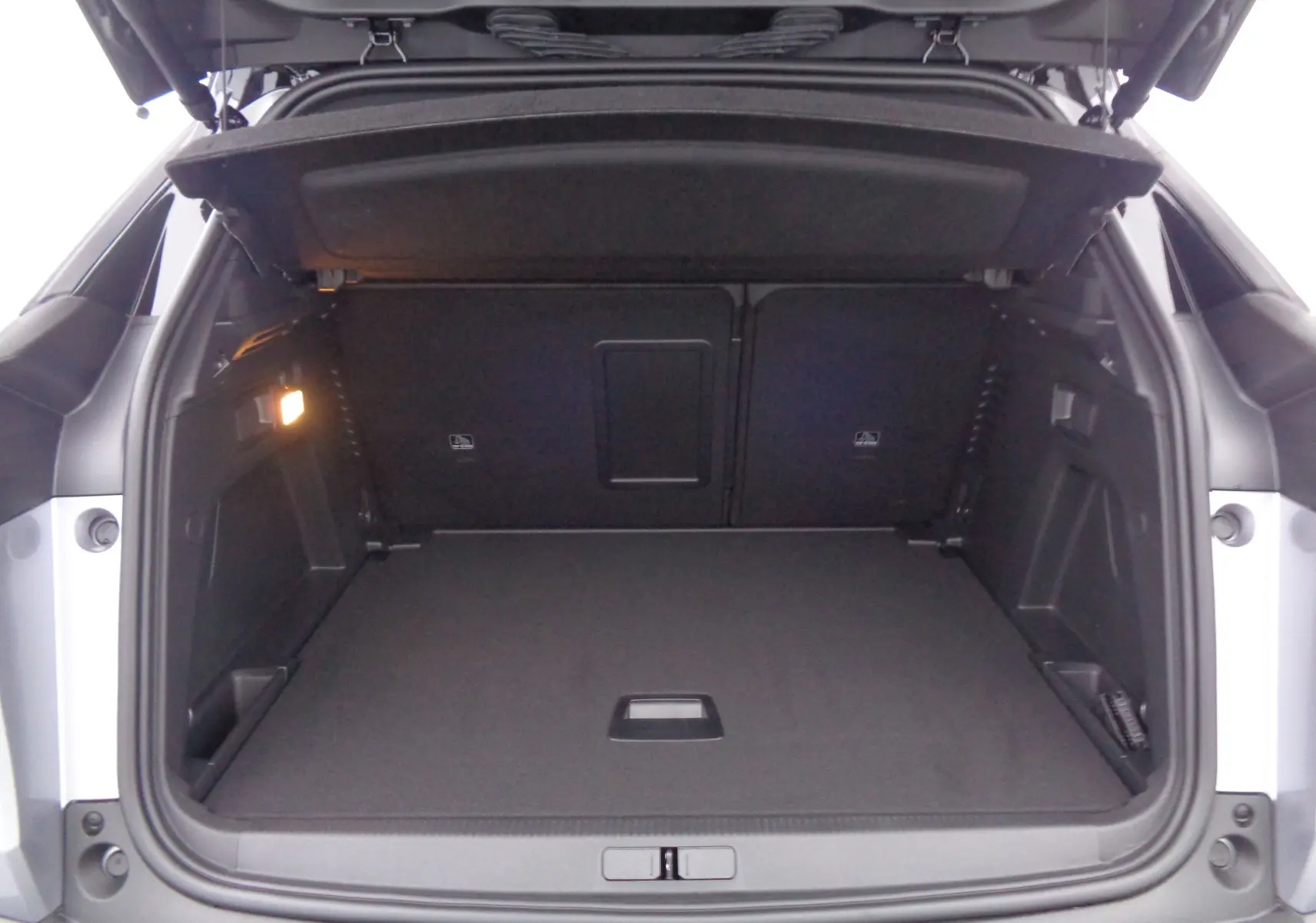 Coffre ouvert d'un Peugeot 3008 gris Artense métal, vue arrière montrant un espace de chargement spacieux et éclairé.