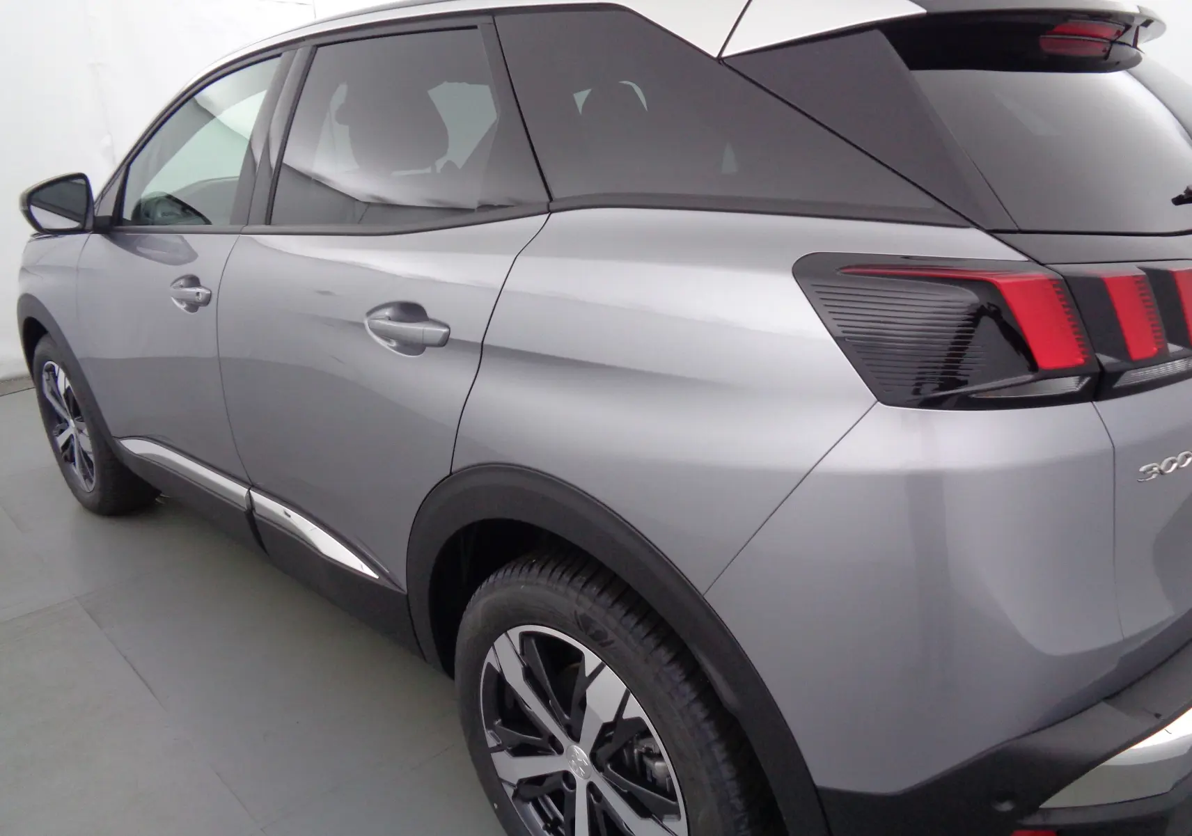 Vue 3/4 arrière droit d'un Peugeot 3008 gris Artense métallisé avec feux arrière à griffes rouges distinctifs.