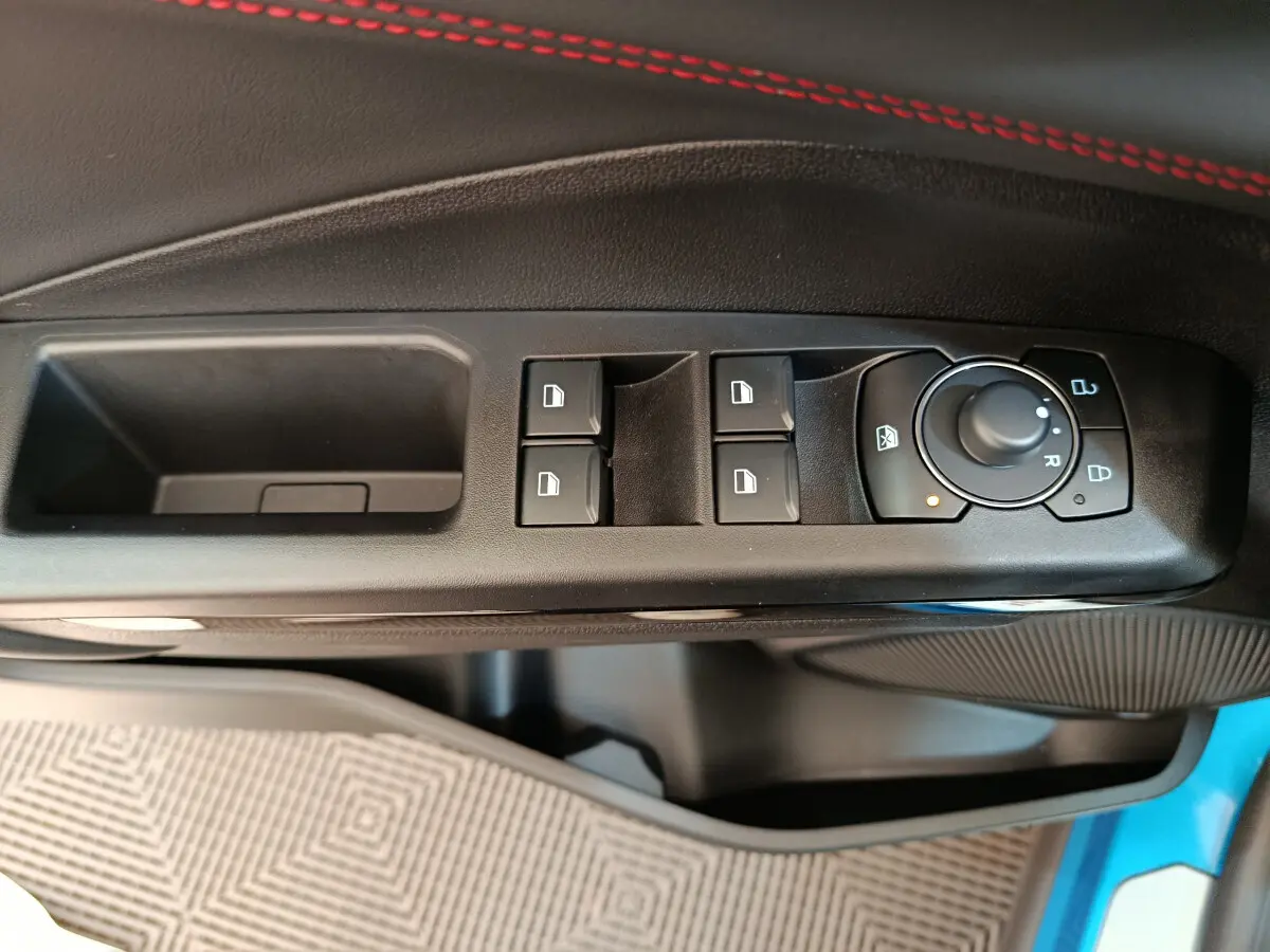 Gros plan sur les commandes de lève-vitres et rétroviseurs côté conducteur du Ford Puma bleu 2025.