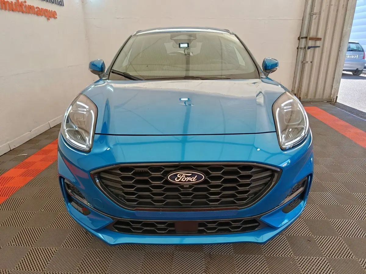 Vue frontale d'une Ford Puma bleu vif avec calandre noire hexagonale et phares LED distinctifs.