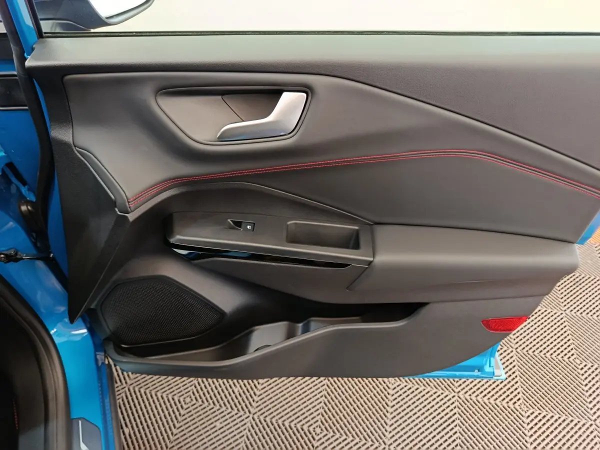 Porte intérieure côté gauche du Ford Puma bleu 2025, avec surpiqûres rouges et commande de vitre intégrée.