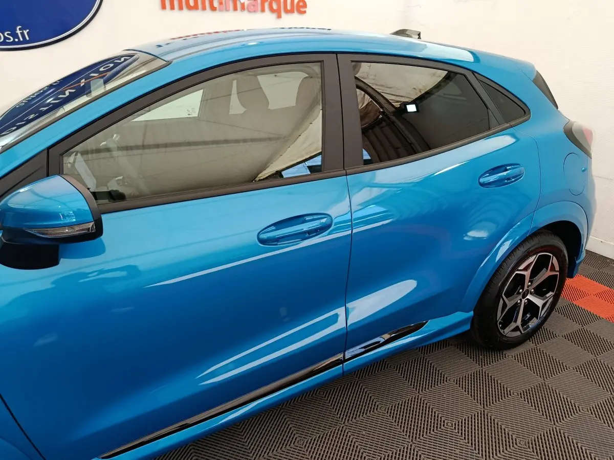 Vue latérale côté gauche du Ford Puma bleu 2025 avec jantes alliage et rétroviseurs noirs intégrant clignotants.