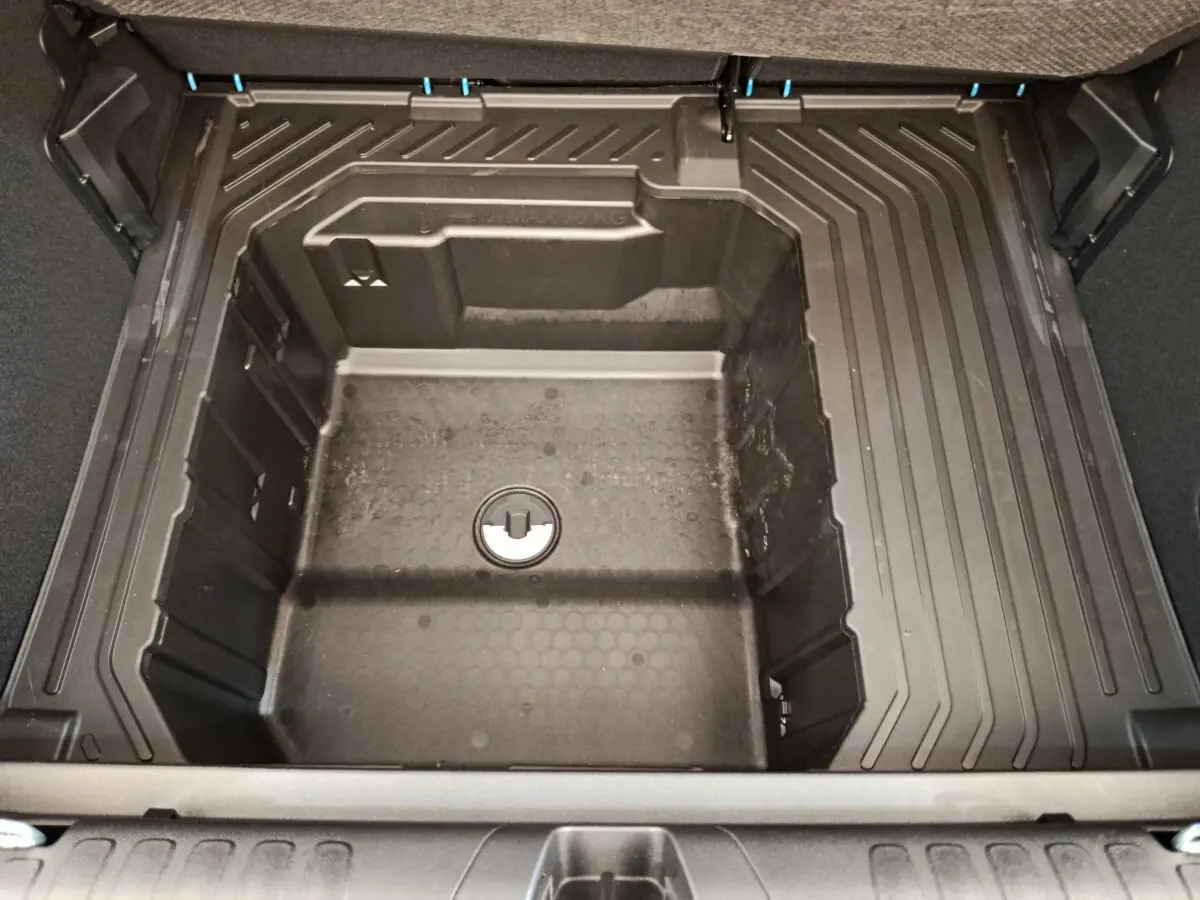 Vue plongeante sur le coffre modulable du Ford Puma 2025, montrant le compartiment de rangement sous tablette en plastique noir.