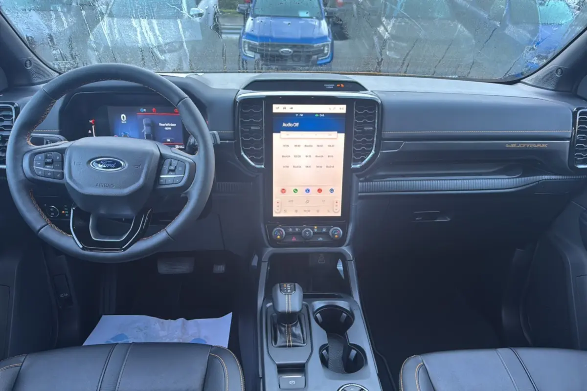 Vue intérieure avant du Ford Ranger 2.3 PHEV Wildtrak Plus 2025 avec tableau de bord numérique et écran tactile central.