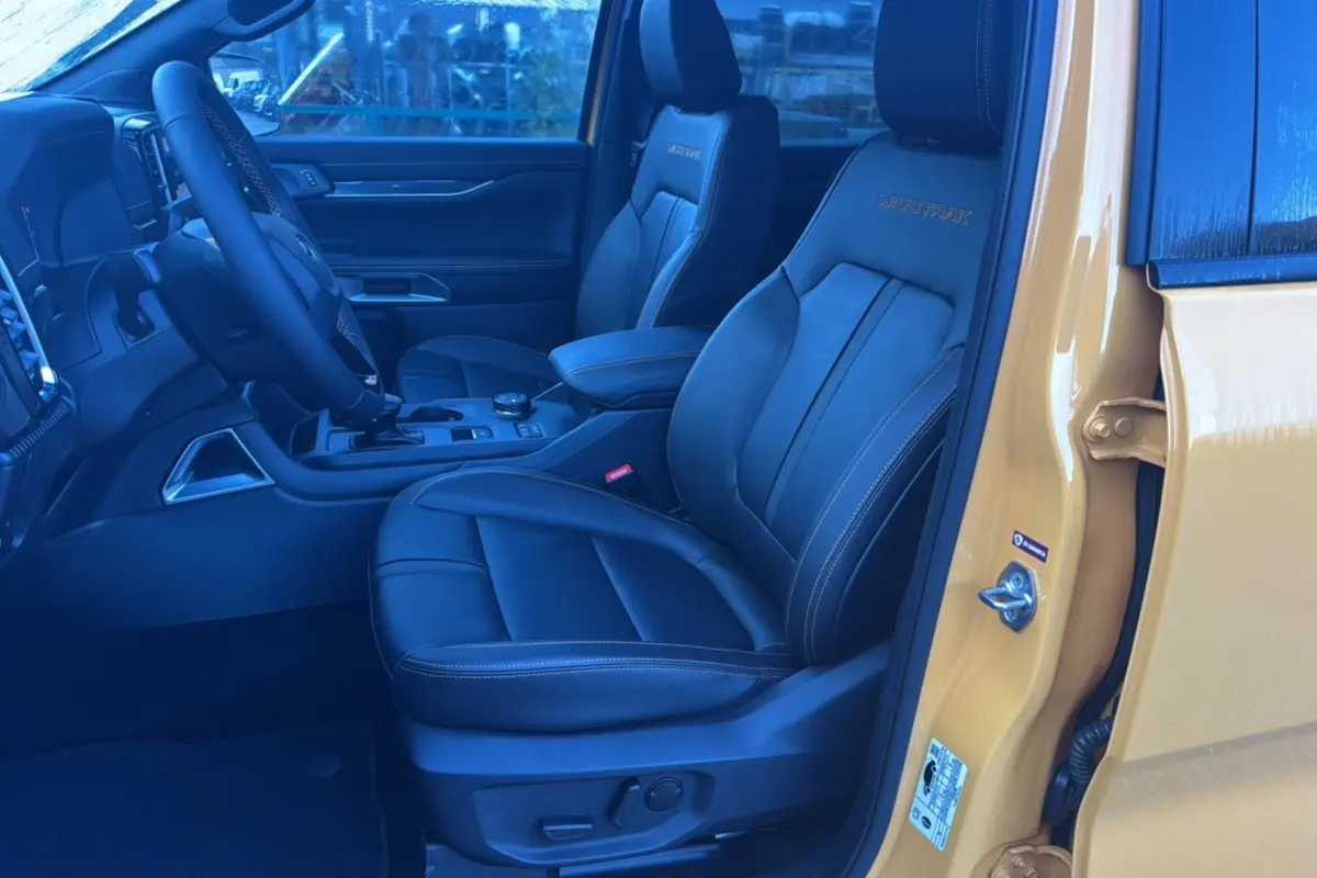 Intérieur du Ford Ranger 2025 Cyber orange, vue côté conducteur ouverte, sièges en cuir noir Wildtrak avec surpiqûres orange.