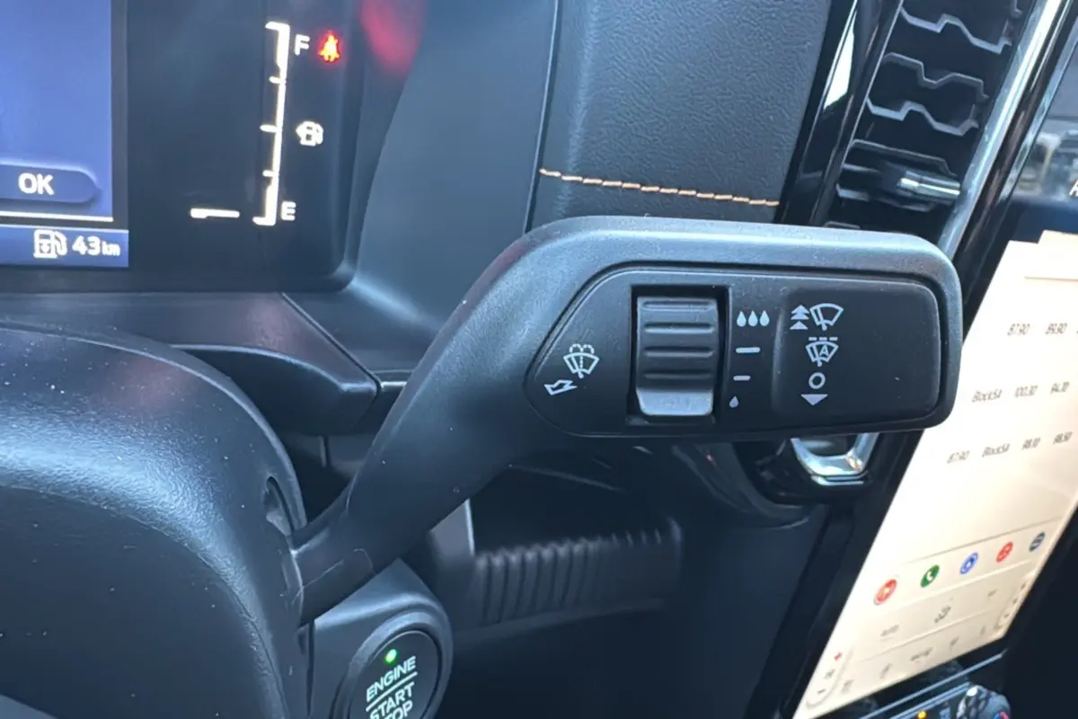 Gros plan sur la commande d’essuie-glace du Ford Ranger 2.3 PHEV 281 Wildtrak Plus 2025, intérieur noir avec surpiqûres orange.