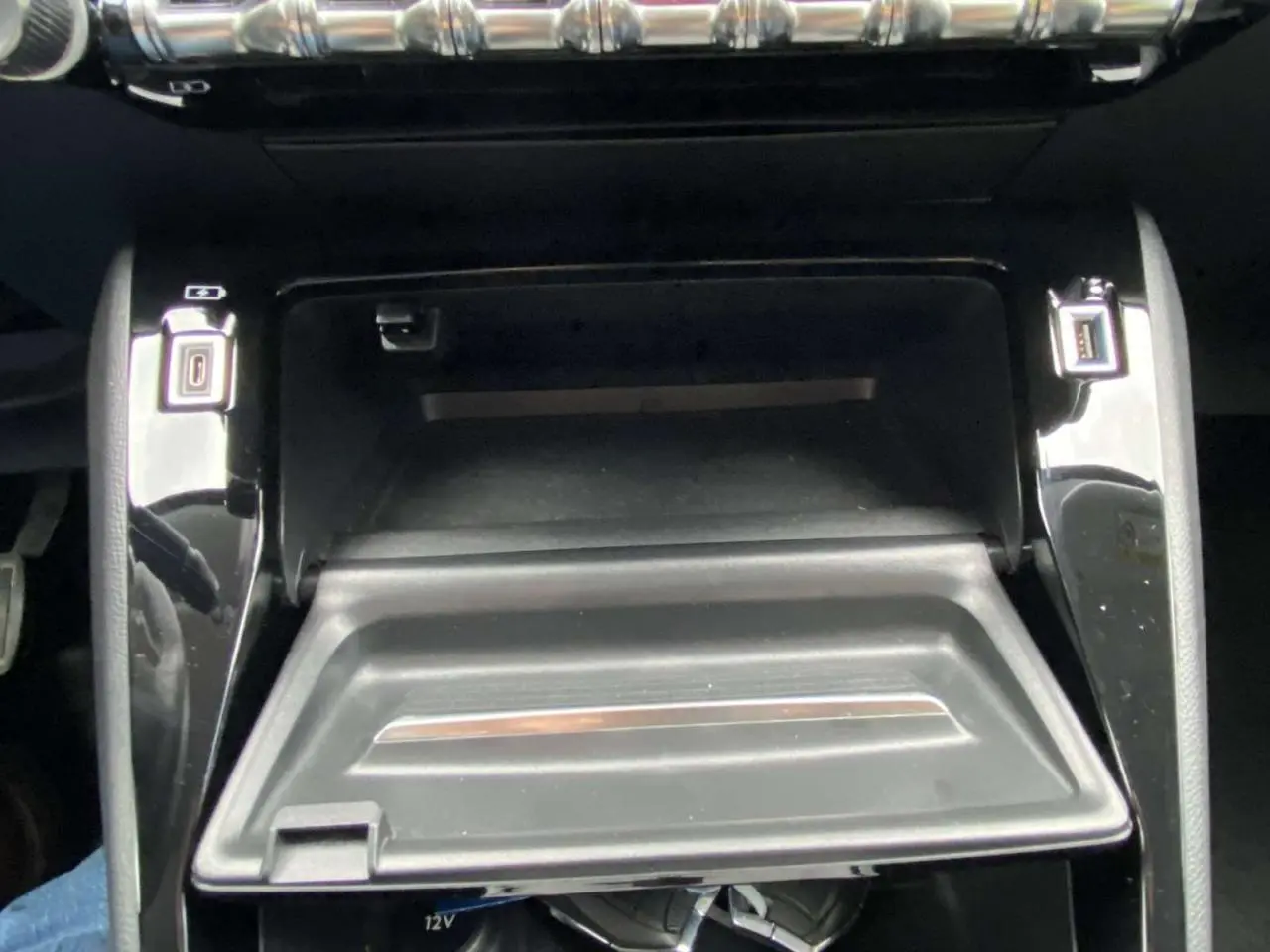 Gros plan sur la console centrale noire du Peugeot 208 1.2i PureTech 2020 avec compartiment ouvert et ports USB visibles.