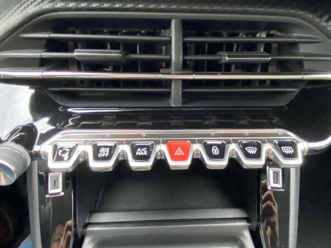 Gros plan sur la console centrale du Peugeot 208 bleu 2020, montrant les commandes climatisation et boutons fonctionnels.