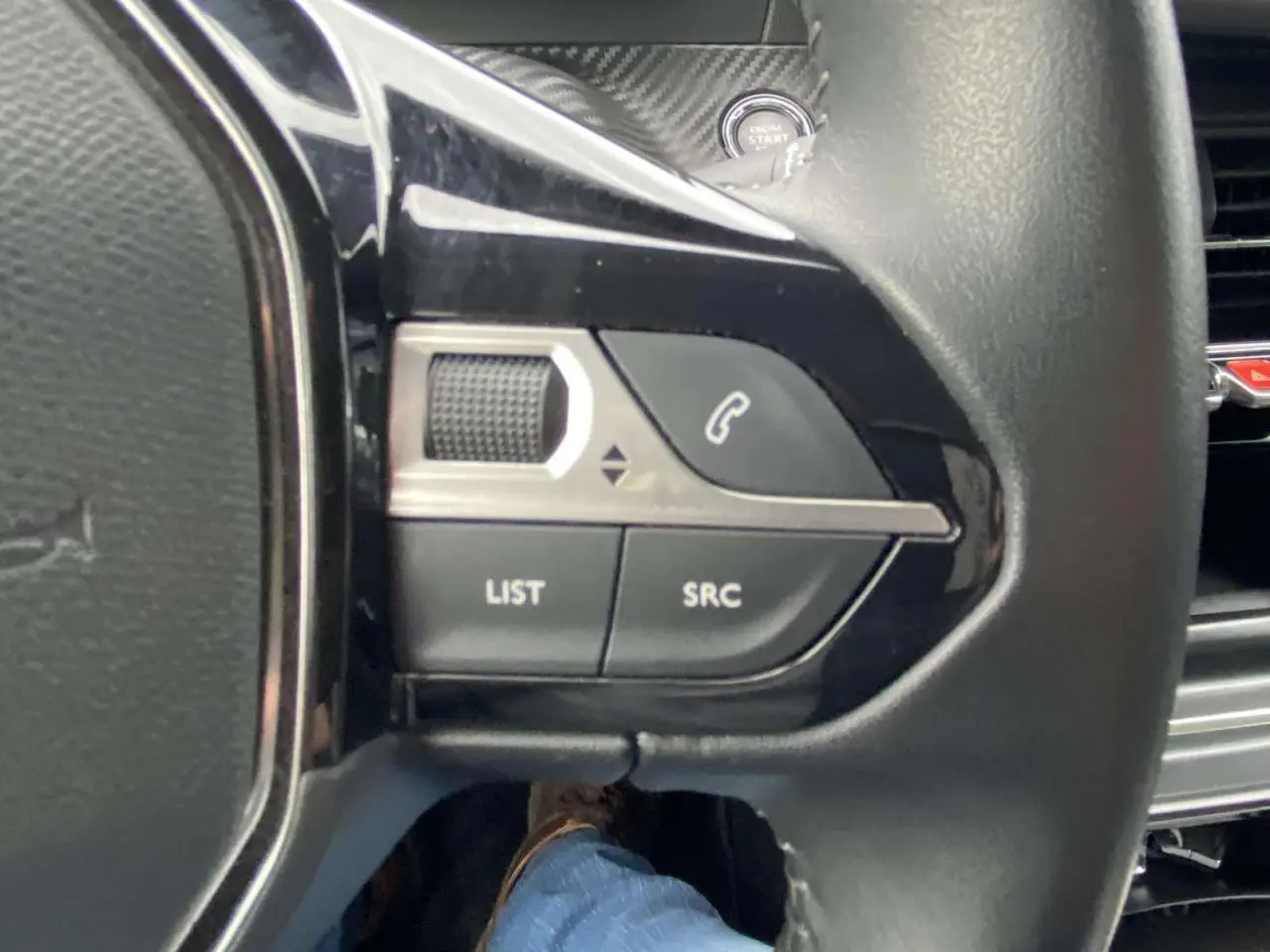 Gros plan sur les commandes gauche du volant noir de la Peugeot 208 2020, avec bouton appel et molette de réglage.