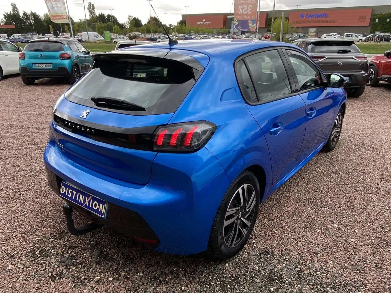 PEUGEOT 208 bleu vue 3/4 arrière droit, avec feux arrière allumés et jantes alliage 16 pouces diamantées.