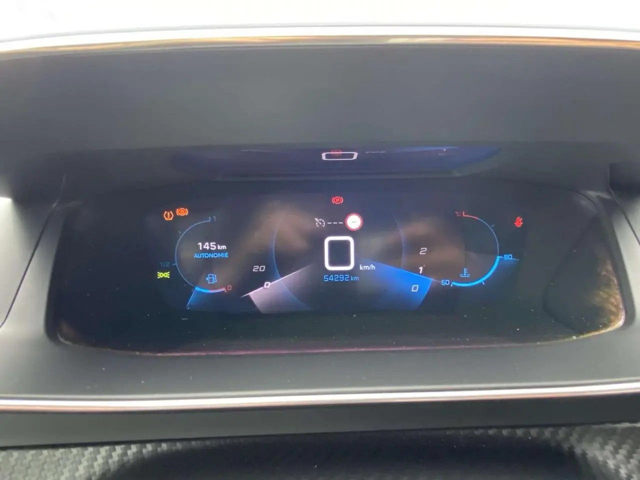 Tableau de bord numérique de Peugeot 208 1.2i PureTech 2020 affichant vitesse à zéro et autonomie 145 km.