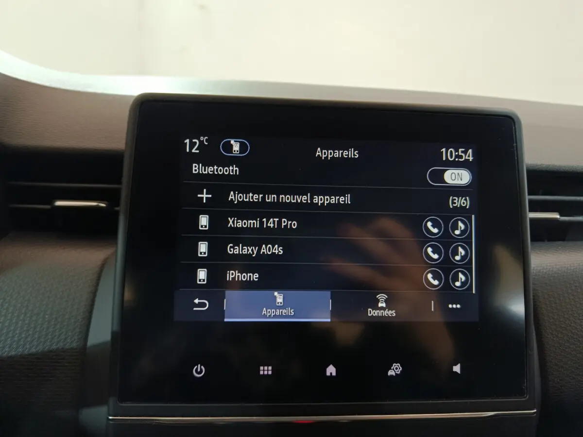 Écran tactile central affichant menu Bluetooth dans l'habitacle d'une Renault Clio Business blanc, vue frontale rapprochée.