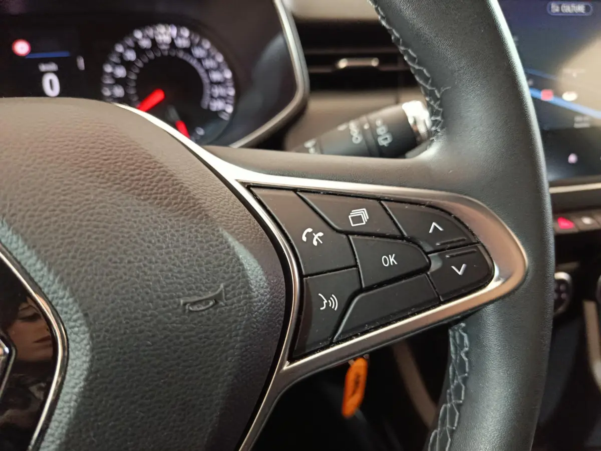 Gros plan sur le volant cuir noir de la Renault Clio Business TCe 90 avec commandes multifonctions et tableau de bord partiellement visible.