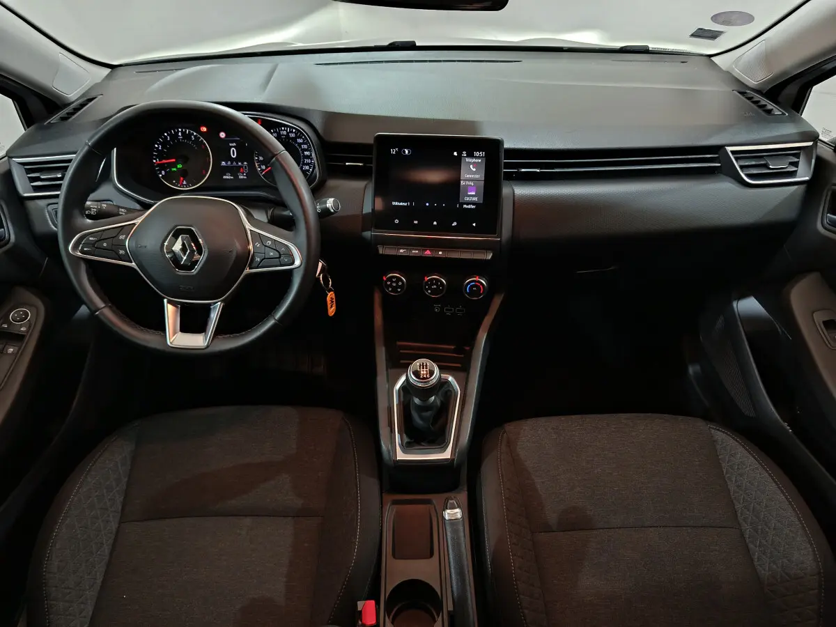 Vue intérieure avant de la Renault Clio Business TCe 90 2021, tableau de bord noir avec écran tactile et volant cuir multifonctions.