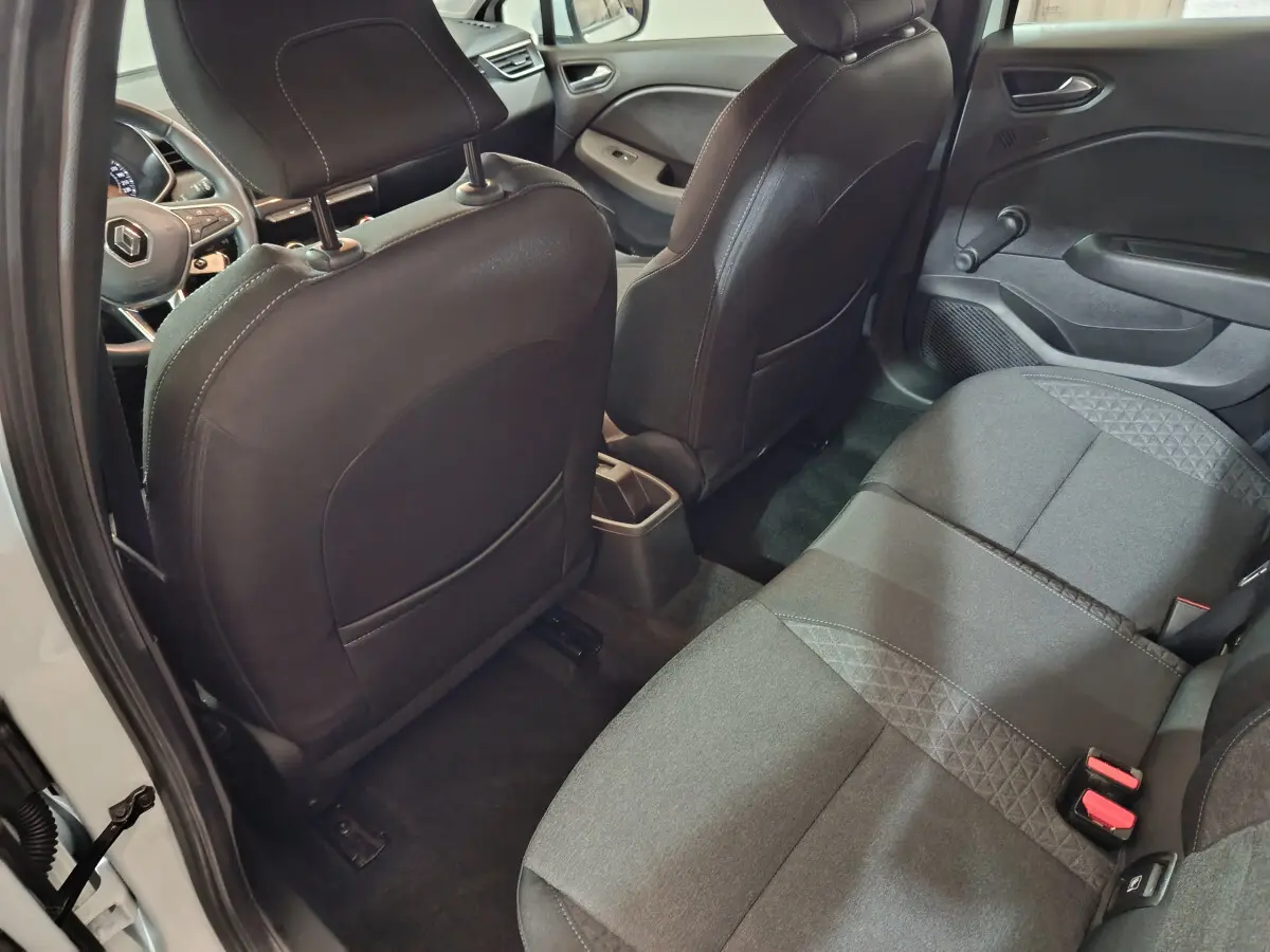 Vue intérieure arrière côté droit de la Renault Clio Business TCe 90 blanche, sièges tissu noir et tableau de bord partiel visible.