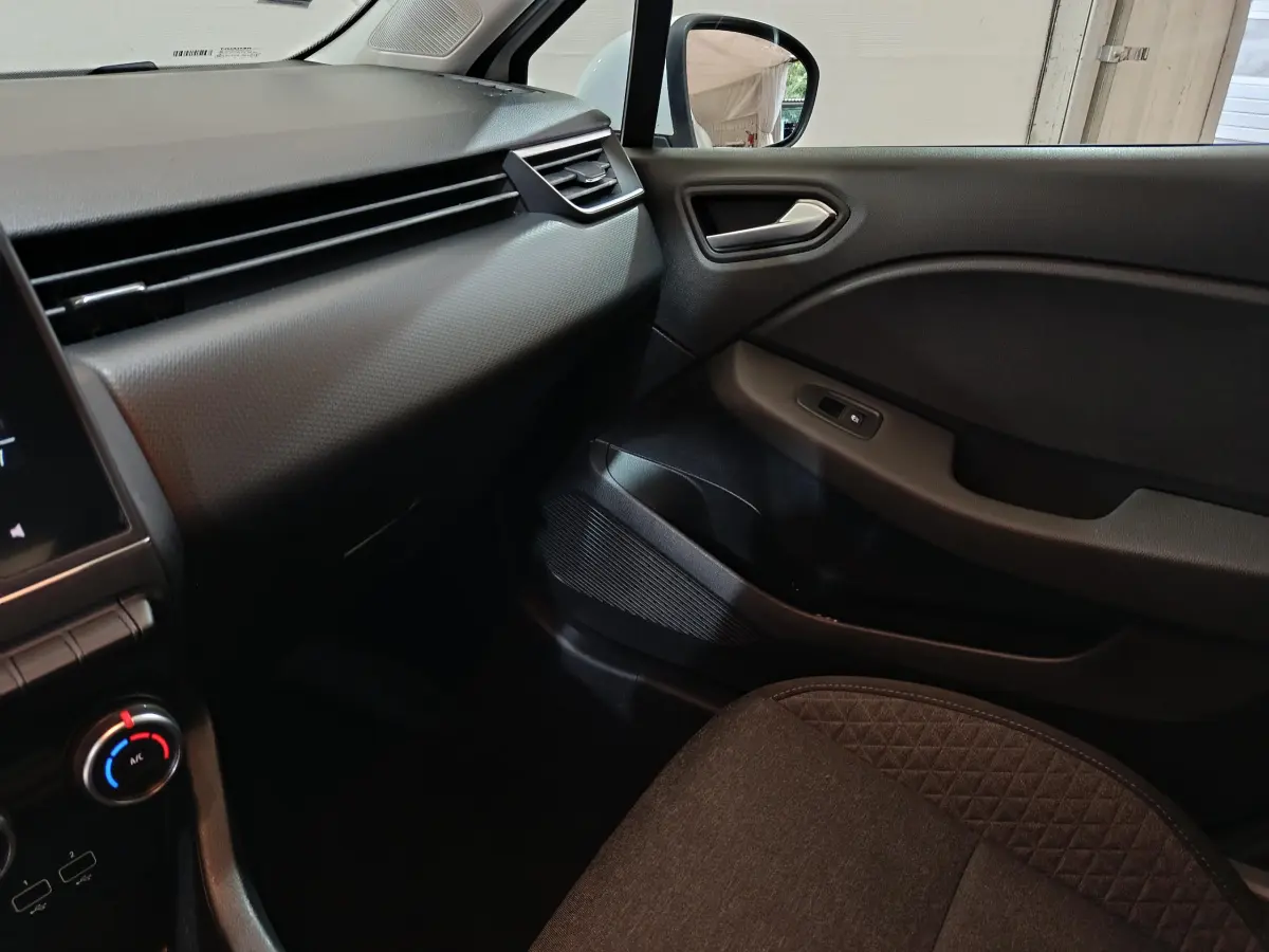 Intérieur côté passager de la Renault Clio Business blanc, montrant tableau de bord et porte avec commande vitre électrique.