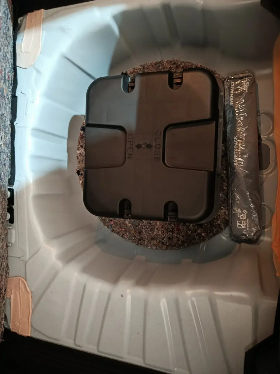 Vue plongeante sur le coffre blanc de la Renault Clio Business TCe 90, montrant le compartiment de rangement avec kit de sécurité.