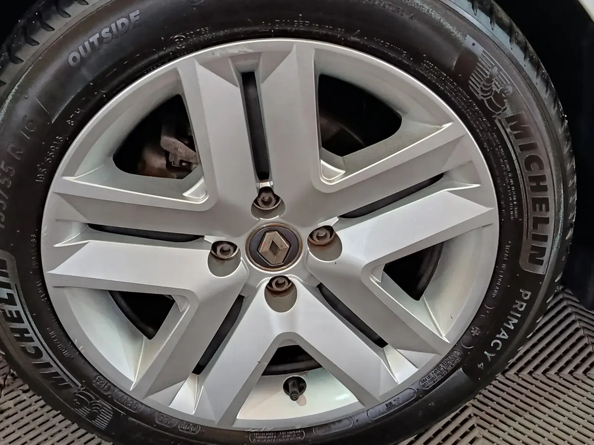 Gros plan sur la jante alliage argentée avec logo Renault au centre d'une Renault Clio blanche.