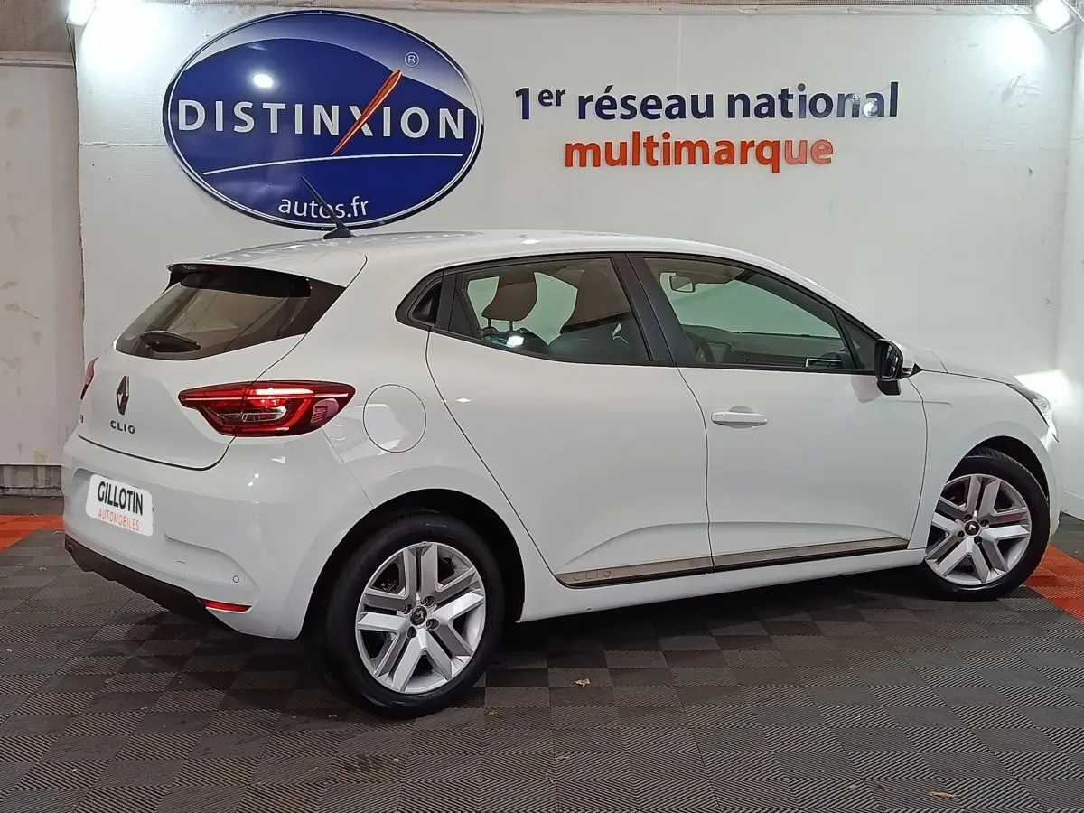 Vue de profil côté gauche d'une Renault Clio Business blanche, avec jantes alliage et feux arrière LED visibles.