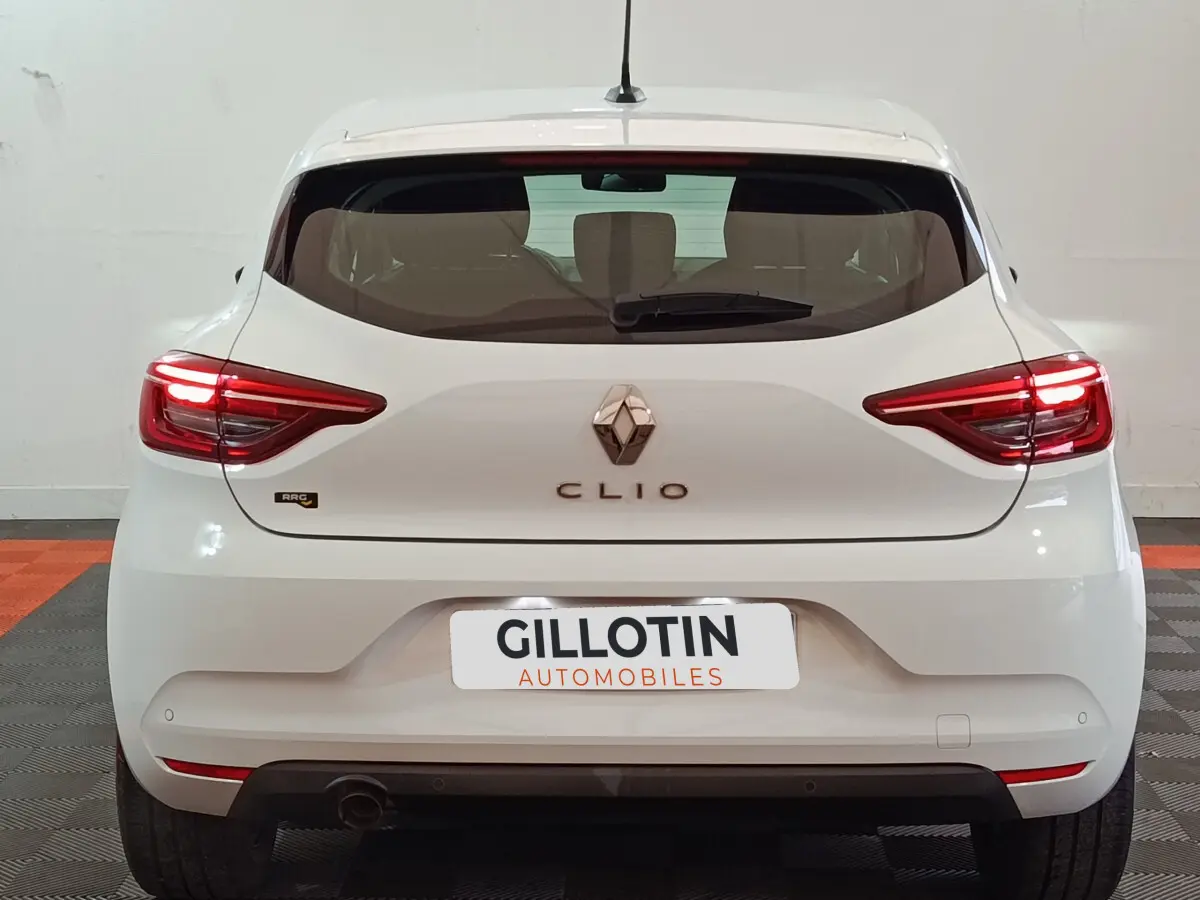 Vue arrière d'une Renault Clio blanche 2021 avec feux LED et logo centré sur un fond intérieur neutre.