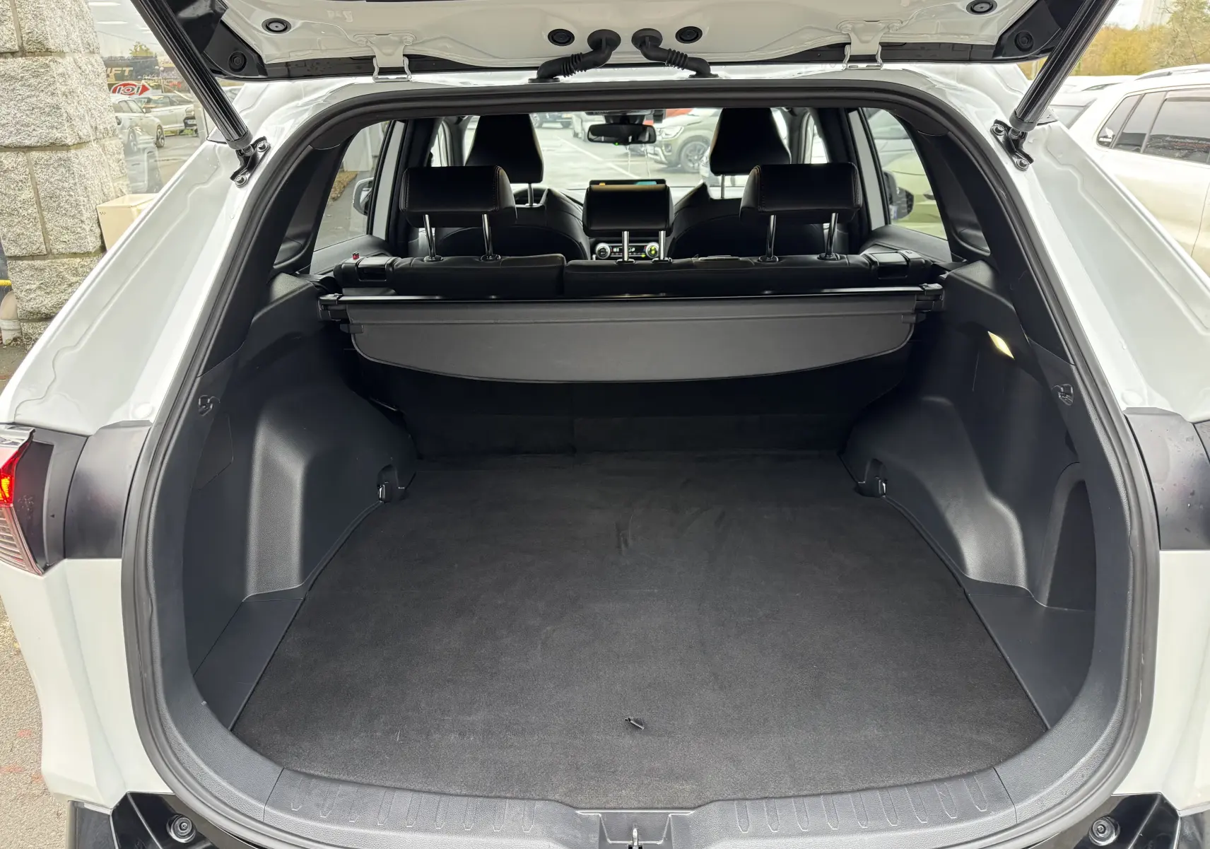 Coffre ouvert vu de l'arrière d'un Suzuki Across blanc 2023, montrant l'espace de chargement et l'intérieur noir.