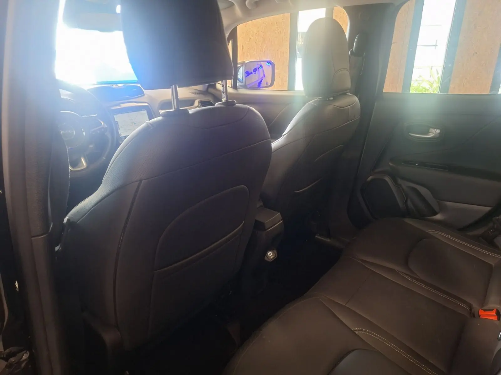 Vue intérieure arrière du Jeep Renegade 2024 noir, mettant en valeur les sièges en cuir noir et la console centrale.