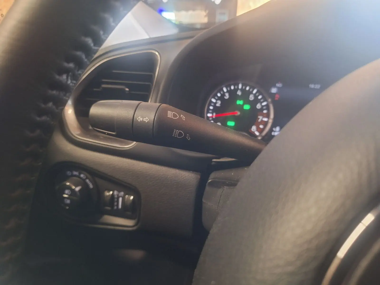 Détail du commodo d'éclairage côté gauche du tableau de bord noir du Jeep Renegade 2024 hybride.