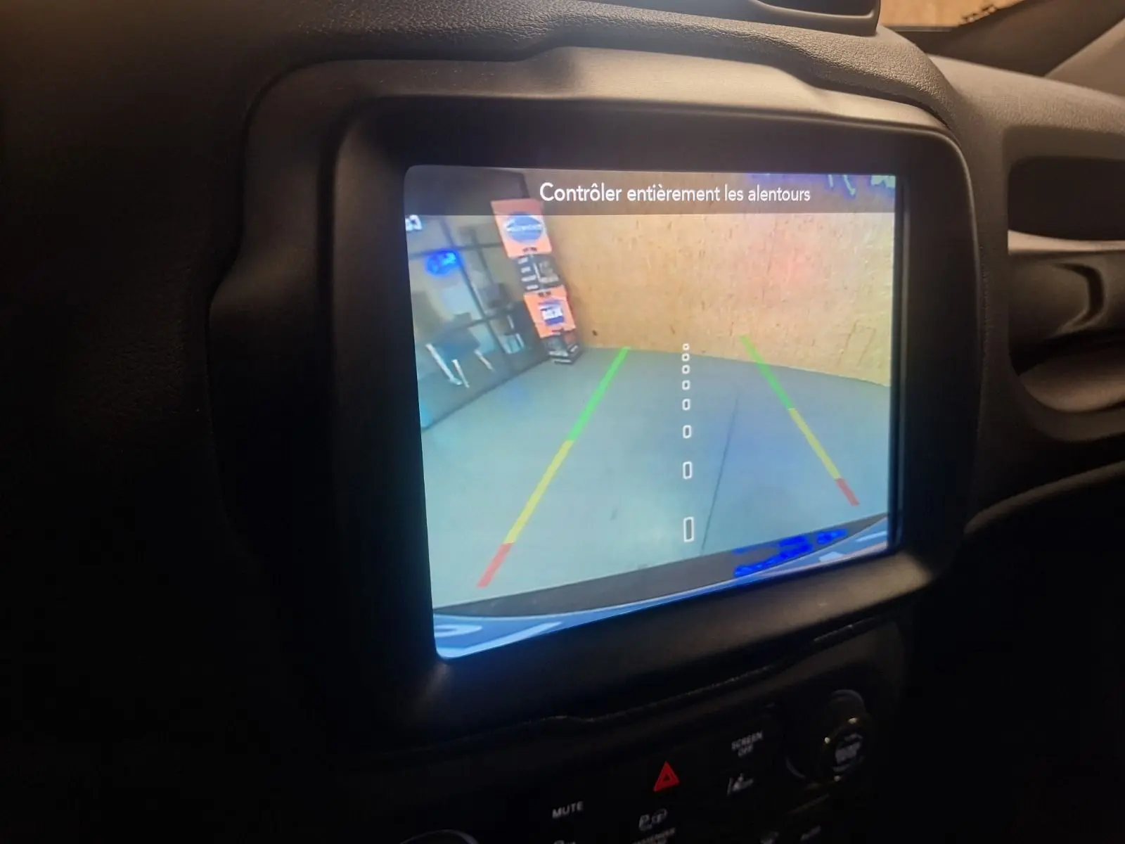 Écran de caméra de recul du Jeep Renegade 2024 affichant les lignes de guidage dans un intérieur noir.