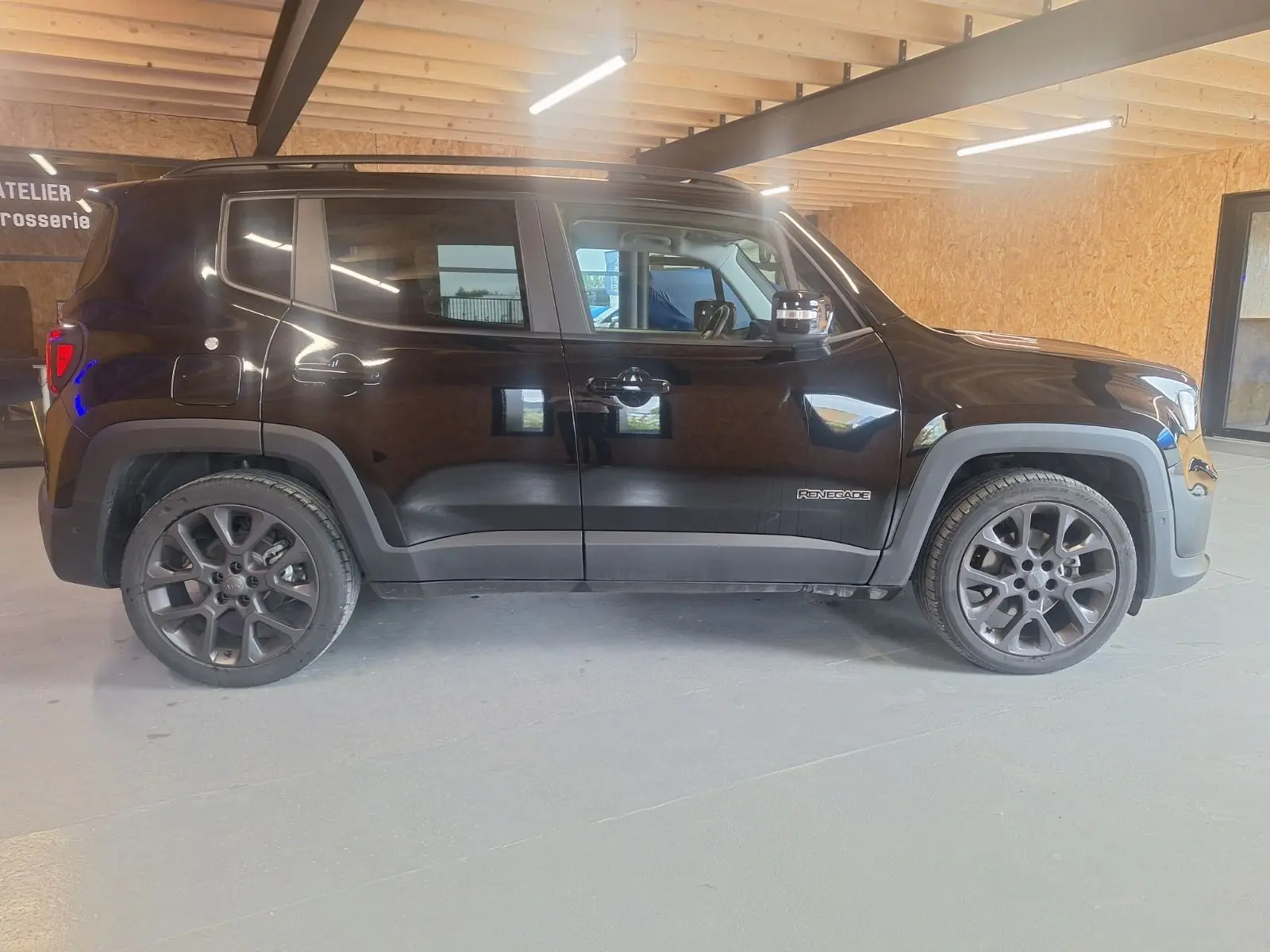 Profil côté gauche d'un Jeep Renegade noir 2024 en version hybride, avec jantes foncées et détails de carrosserie marqués.