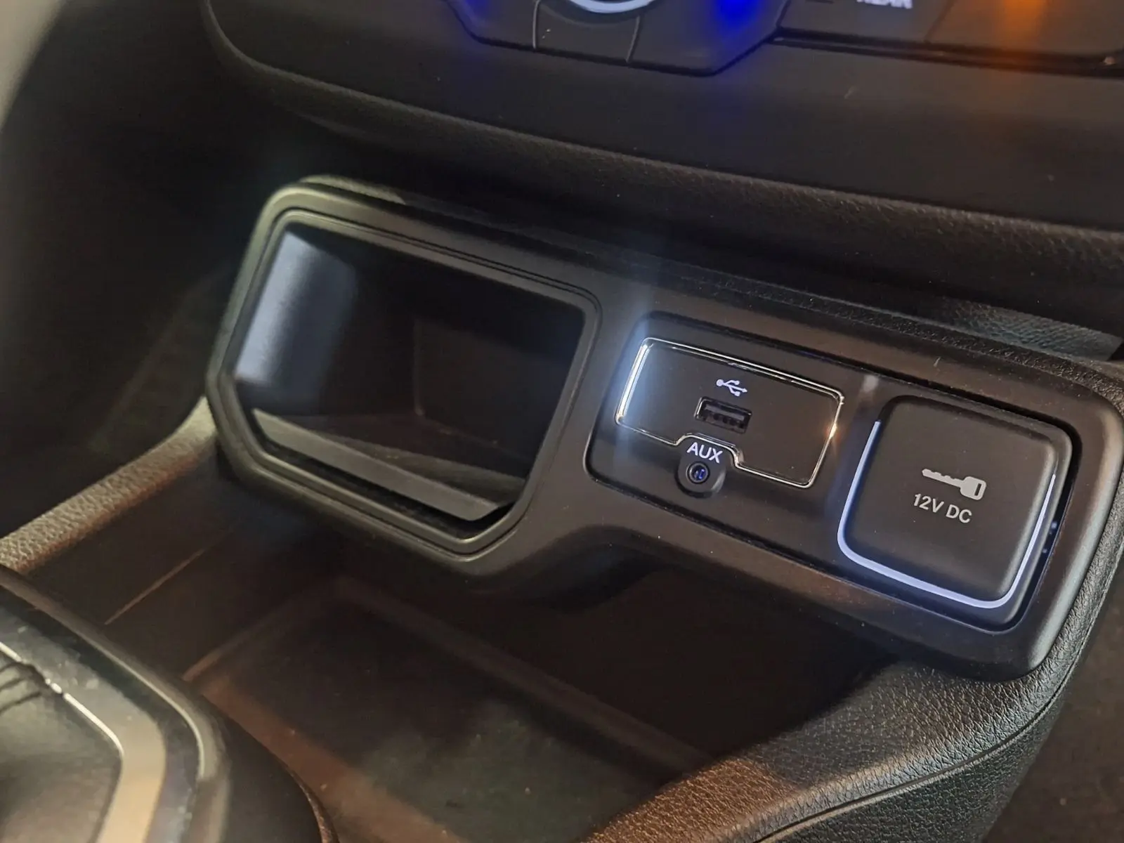 Gros plan sur la console centrale noire du Jeep Renegade 2024, montrant les ports USB, AUX et prise 12V DC.