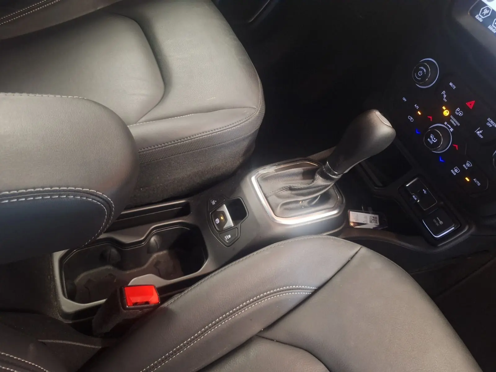 Vue rapprochée de la console centrale et levier de vitesse automatique du Jeep Renegade noir, intérieur cuir noir.