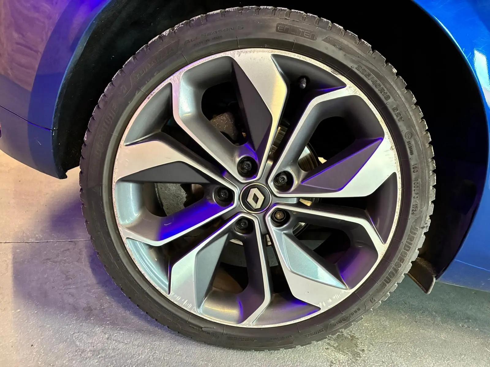 Gros plan sur la jante alliage grise à design moderne de la Renault Mégane bleu visible au-dessus du pneu.