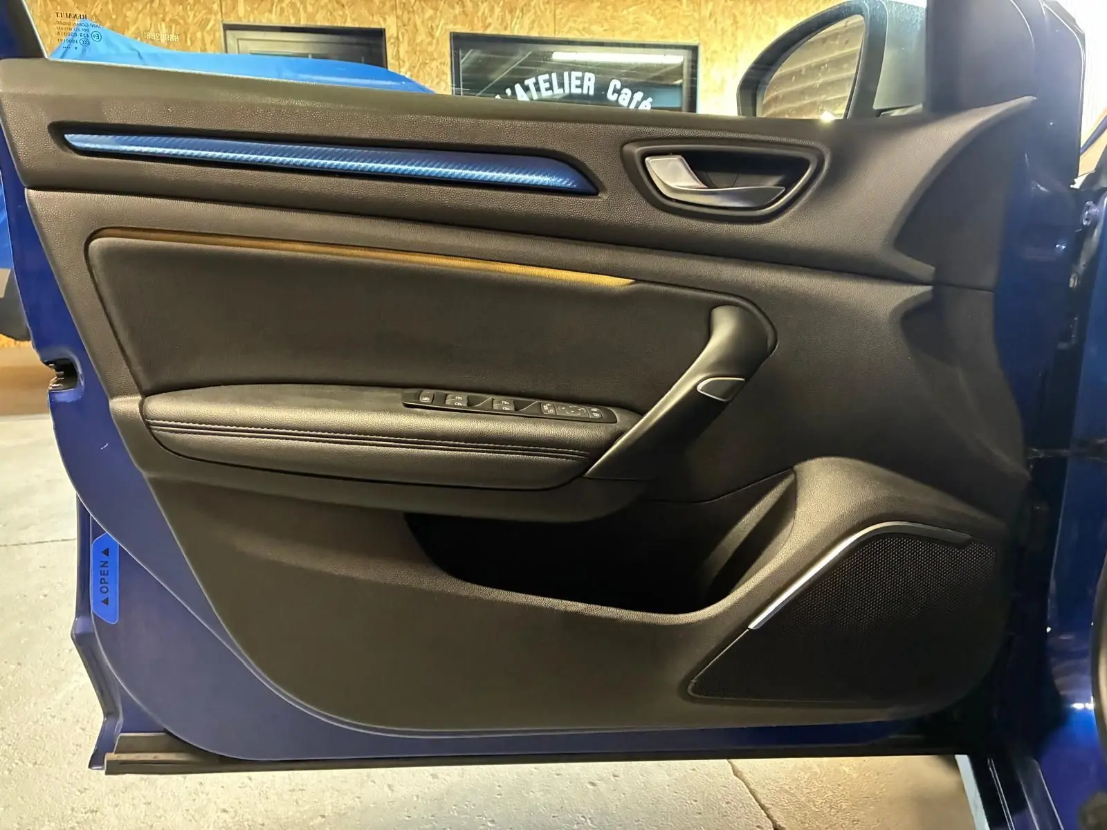 Vue intérieure de la porte avant gauche de la Renault Mégane bleu 2019, avec garniture noire et bande décorative bleue.