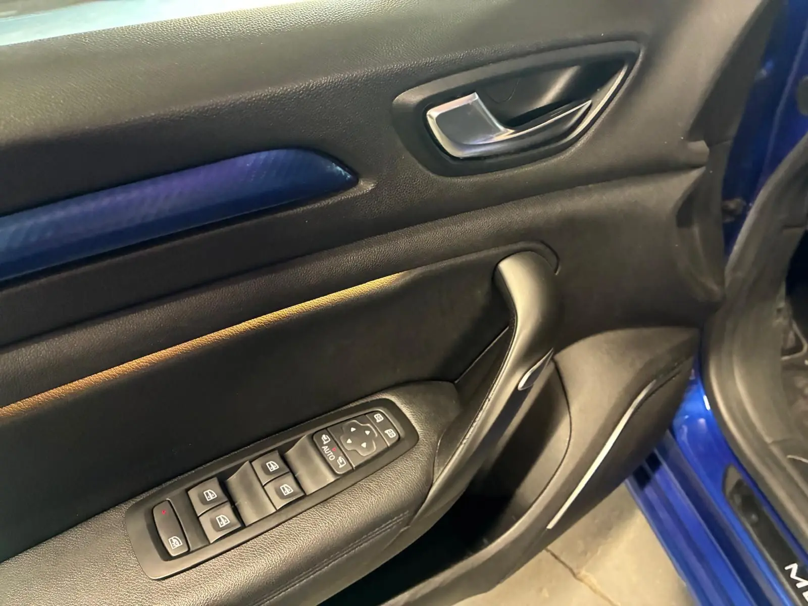 Vue rapprochée de la porte avant gauche de la Renault Mégane bleu, avec commandes électriques et insert décoratif bleu.