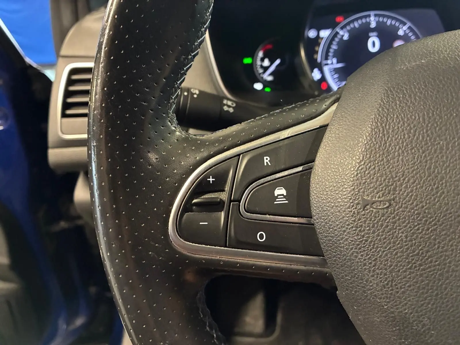 Gros plan sur le volant en cuir perforé noir de la Renault Mégane 1.7 BlueDCI 150 GT Line, avec commandes intégrées.