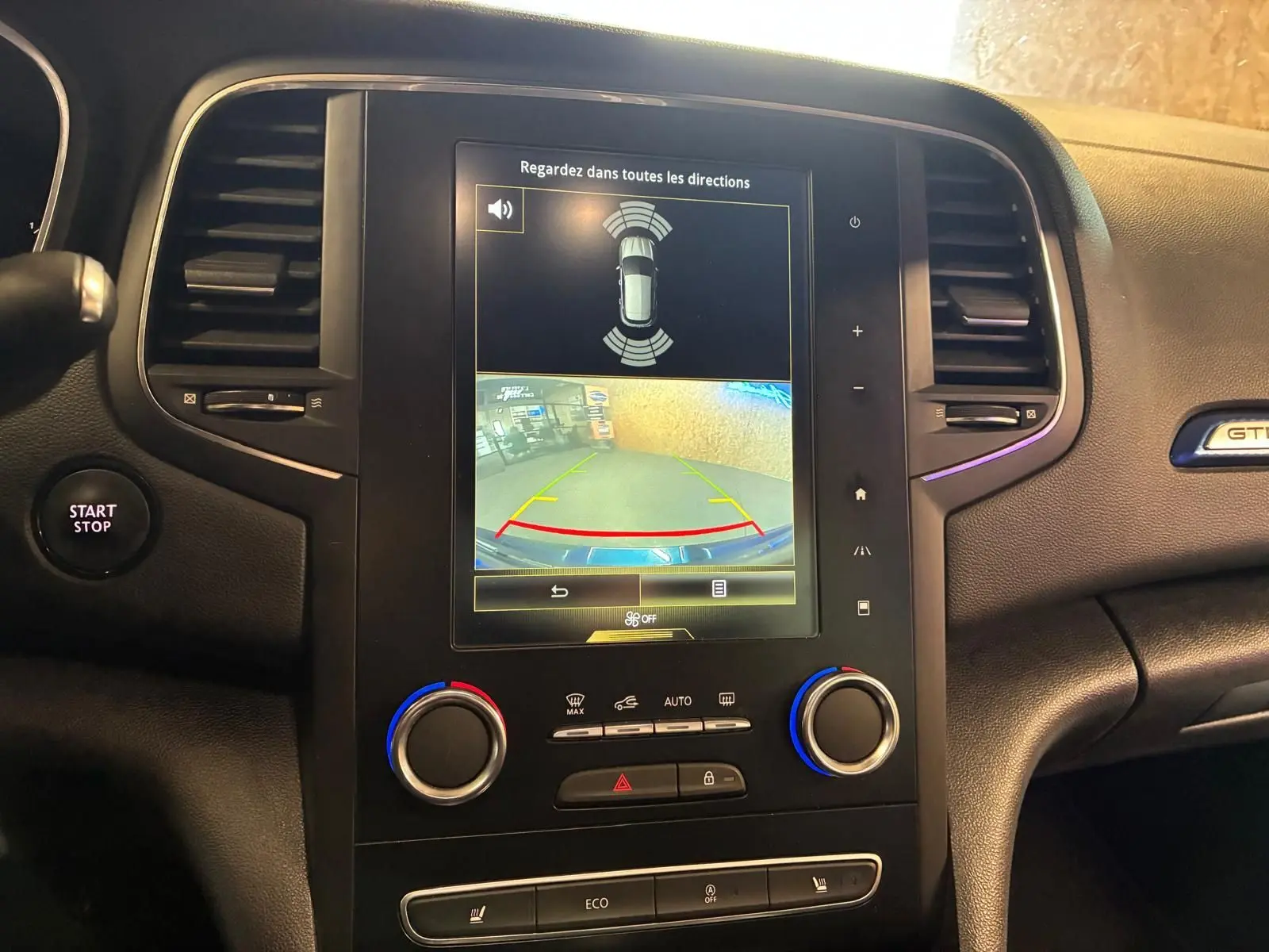 Vue rapprochée de la console centrale de la Renault Mégane GT Line 2019, écran tactile avec caméra de recul et commandes climatisation.