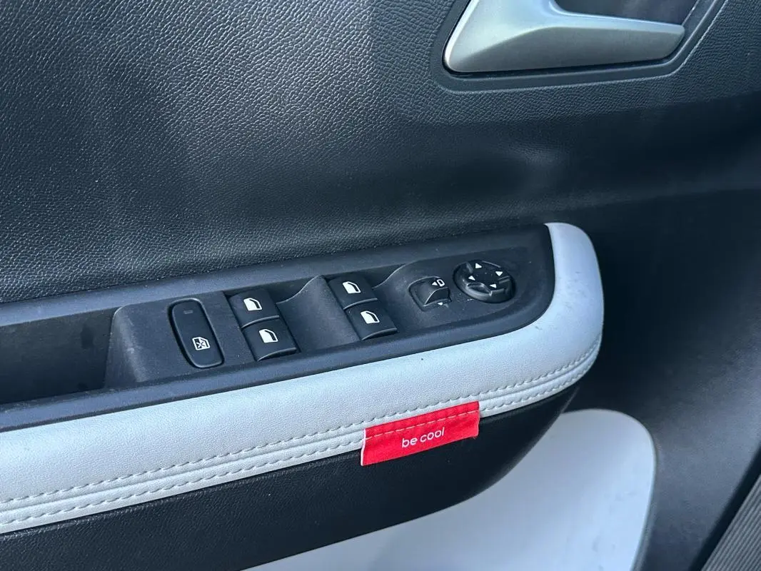 Détail de la porte côté conducteur de la Citroën C3 noire 2025, avec commandes électriques et étiquette rouge "be cool".