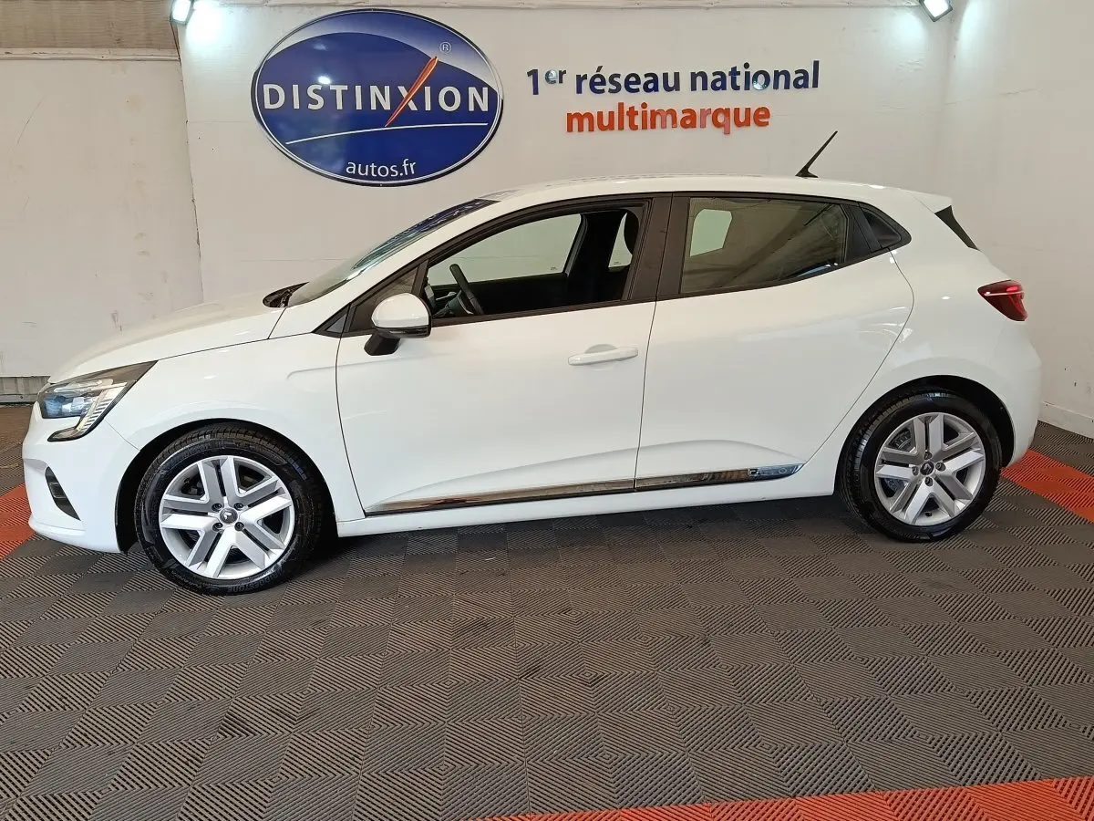 Profil droit d'une Renault Clio Business Blue dCi 100 blanche, avec jantes alliage et logo distinctif sur la porte arrière.