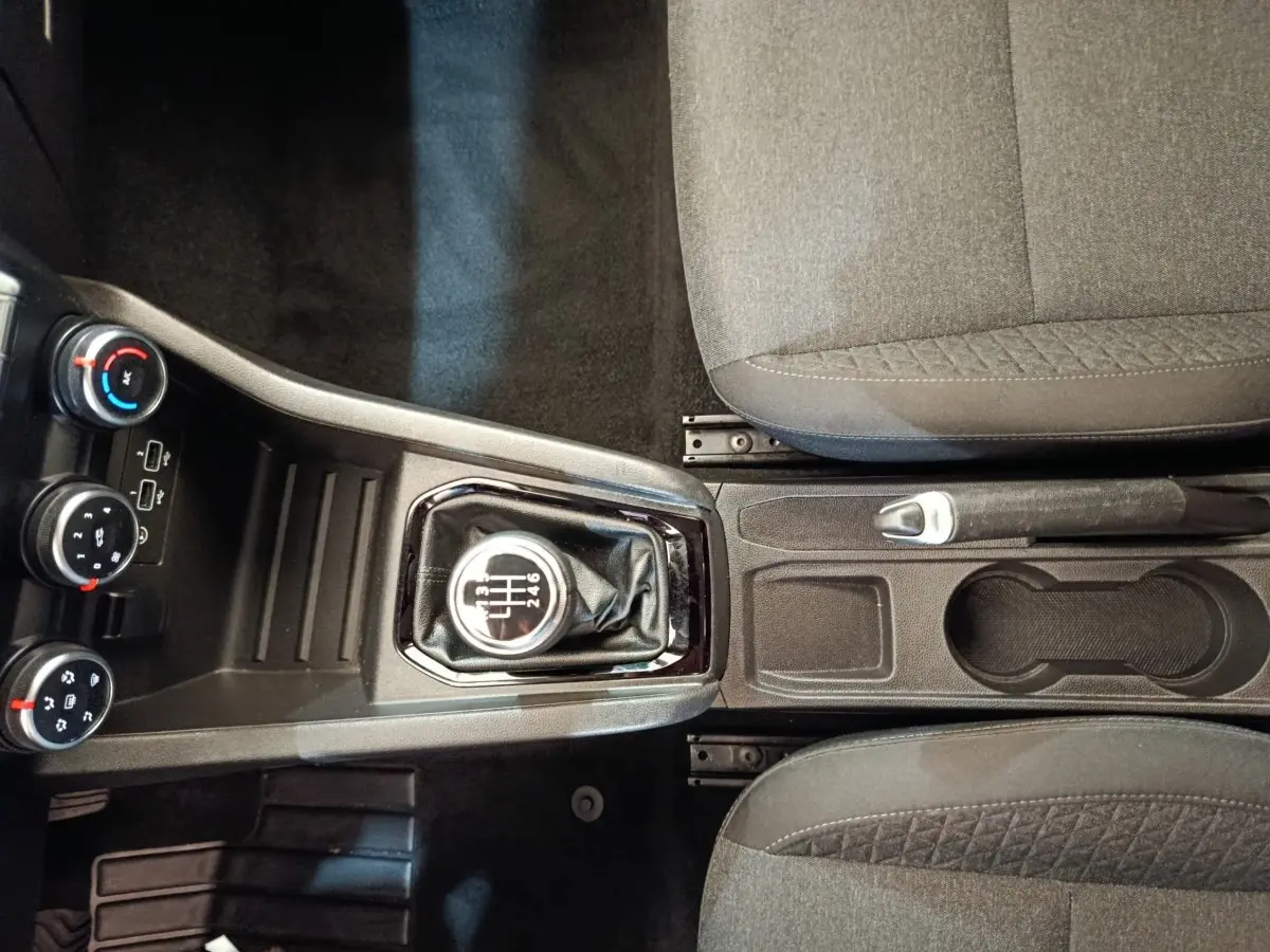Vue de dessus de la console centrale de la Renault Clio Business Blue dCi 100 blanche, avec levier de vitesses manuel et frein à main entre sièges gris.