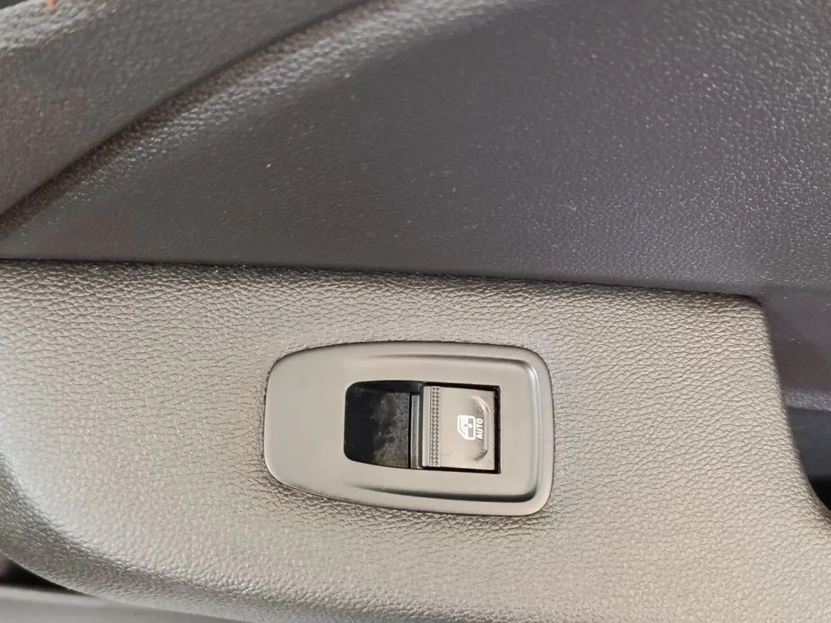 Gros plan sur le bouton de commande de la vitre électrique côté conducteur, intérieur noir texturé de Renault Clio blanc 2022.