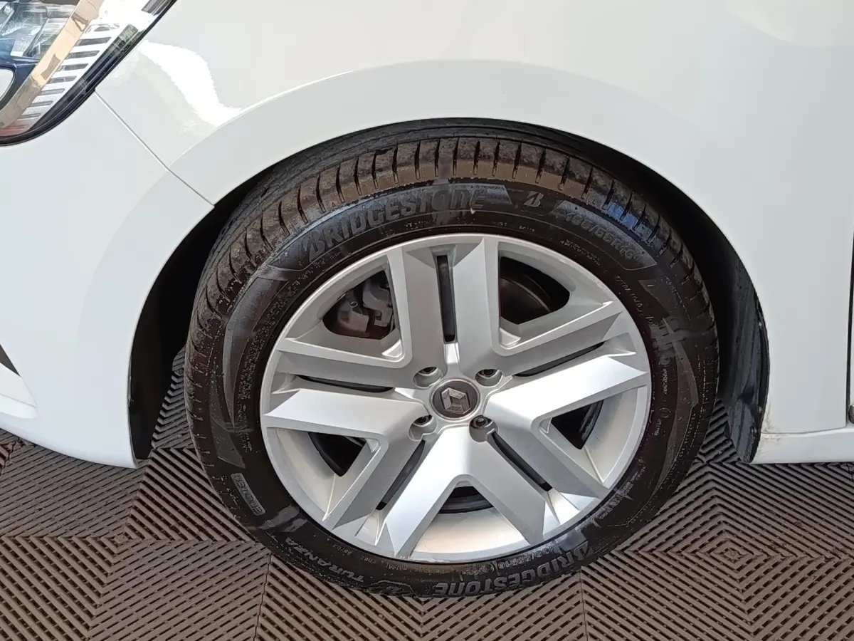 Gros plan sur la roue avant droite d’une Renault Clio blanche, avec jante alliage et pneu Bridgestone.