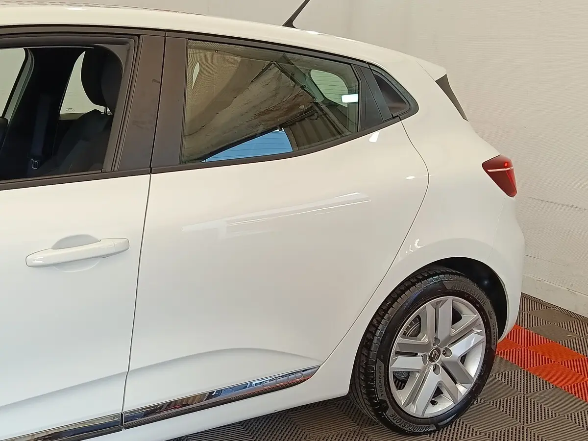 Vue côté droit arrière d'une Renault Clio Business Blue dCi 100 blanche avec jantes alliage et poignées de porte ton carrosserie.