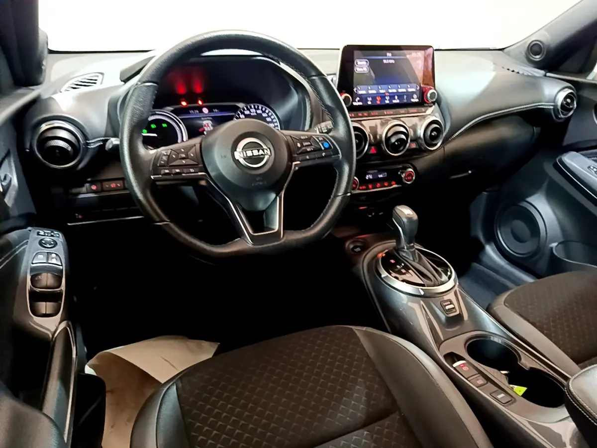 Vue intérieure côté conducteur du Nissan Juke Hybrid 143 Business+ 2023 avec volant cuir, écran tactile et levier de vitesse automatique.
