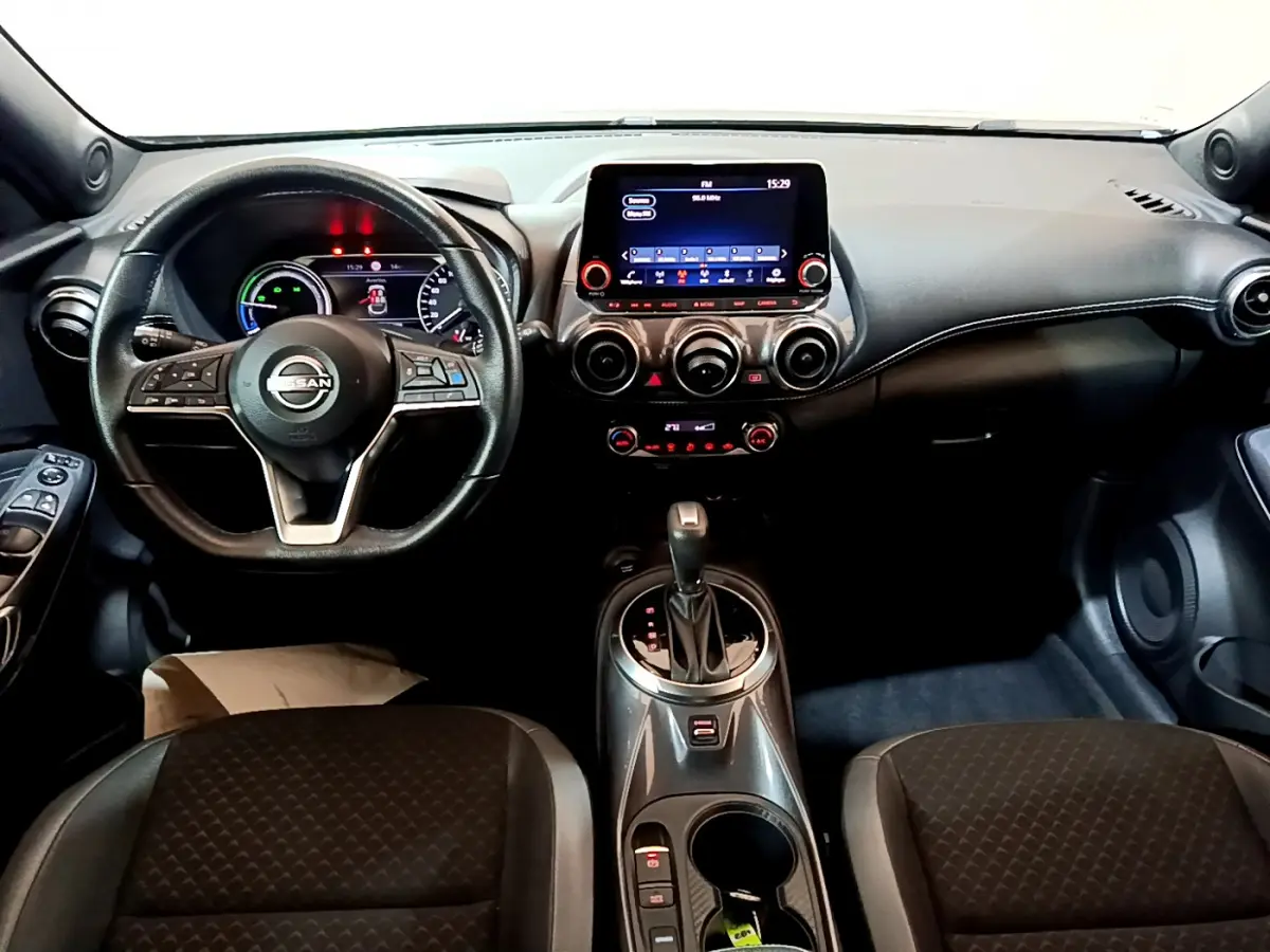 Vue intérieure avant du Nissan Juke Hybrid 143 Business+ 2023, tableau de bord noir avec écran tactile central et volant multifonctions.
