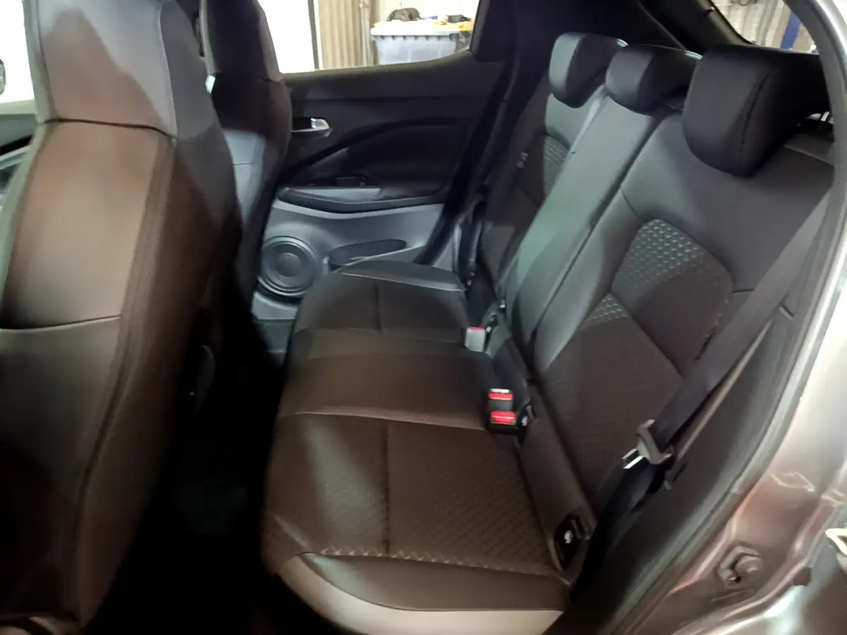 Vue côté droit de la banquette arrière en cuir noir du Nissan Juke Hybrid 143 Business+ 2023 avec portière ouverte.