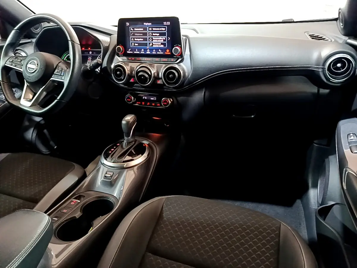 Intérieur du Nissan Juke Hybrid 143 Business+ 2023, vue avant centrée sur tableau de bord et console gris foncé.
