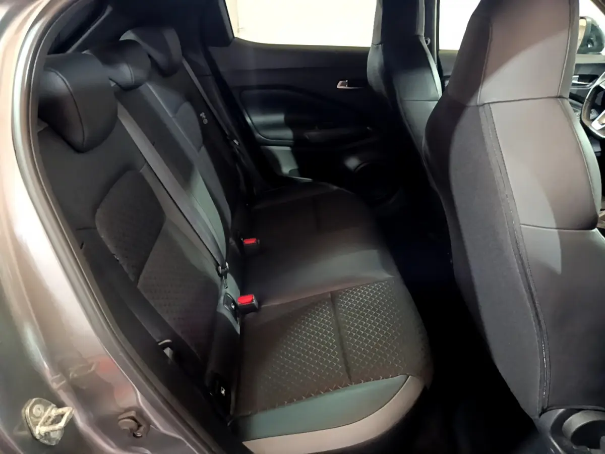 Vue intérieure sur la banquette arrière noire du Nissan Juke Hybrid 143 Business+ gris foncé, avec sièges tissu et cuir.