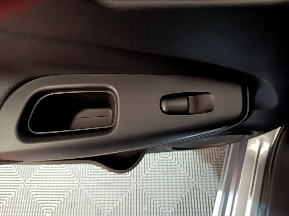 Poignée intérieure et commande de verrouillage côté gauche de la porte d'une Nissan Juke Hybrid gris foncé 2023.