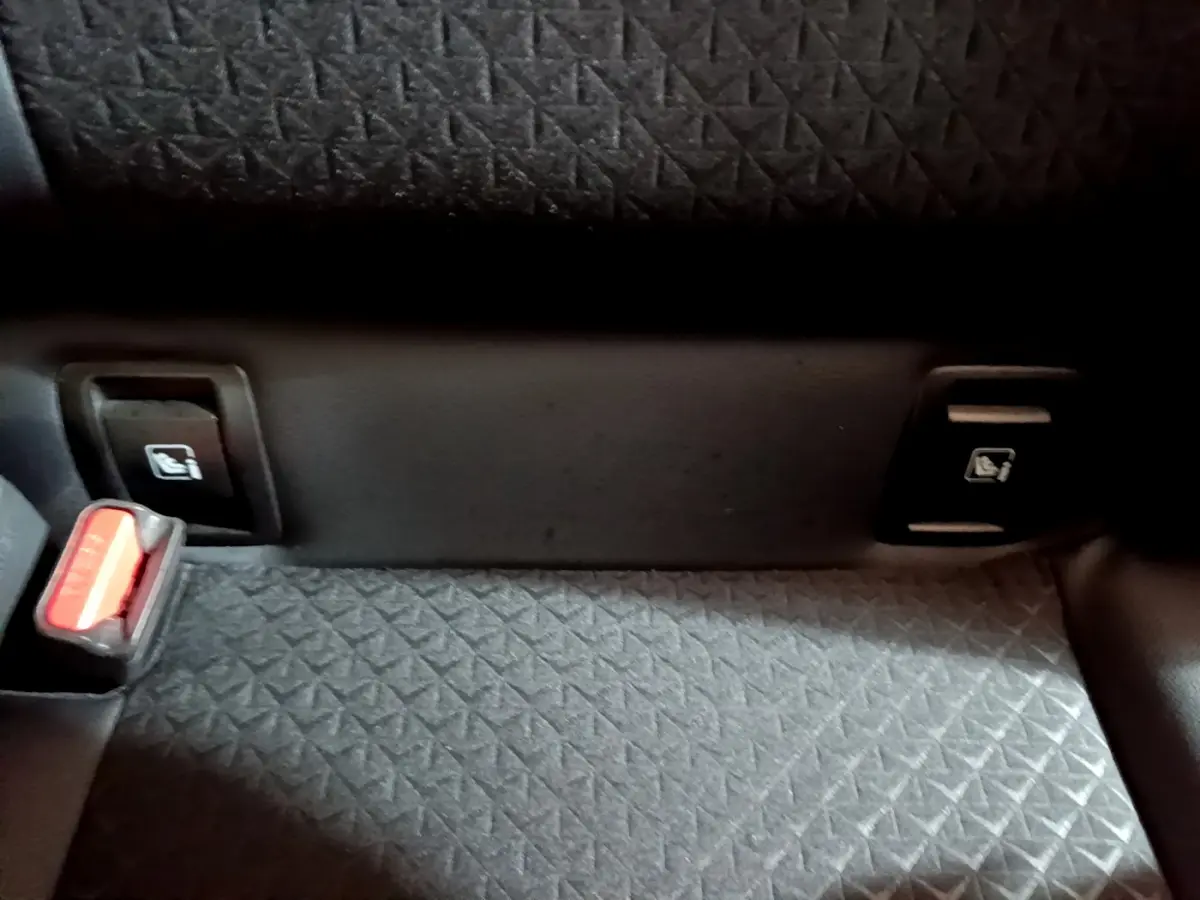 Détail de la banquette arrière grise avec boutons de rabattement des sièges et ceinture de sécurité du Nissan Juke Hybrid 2023.