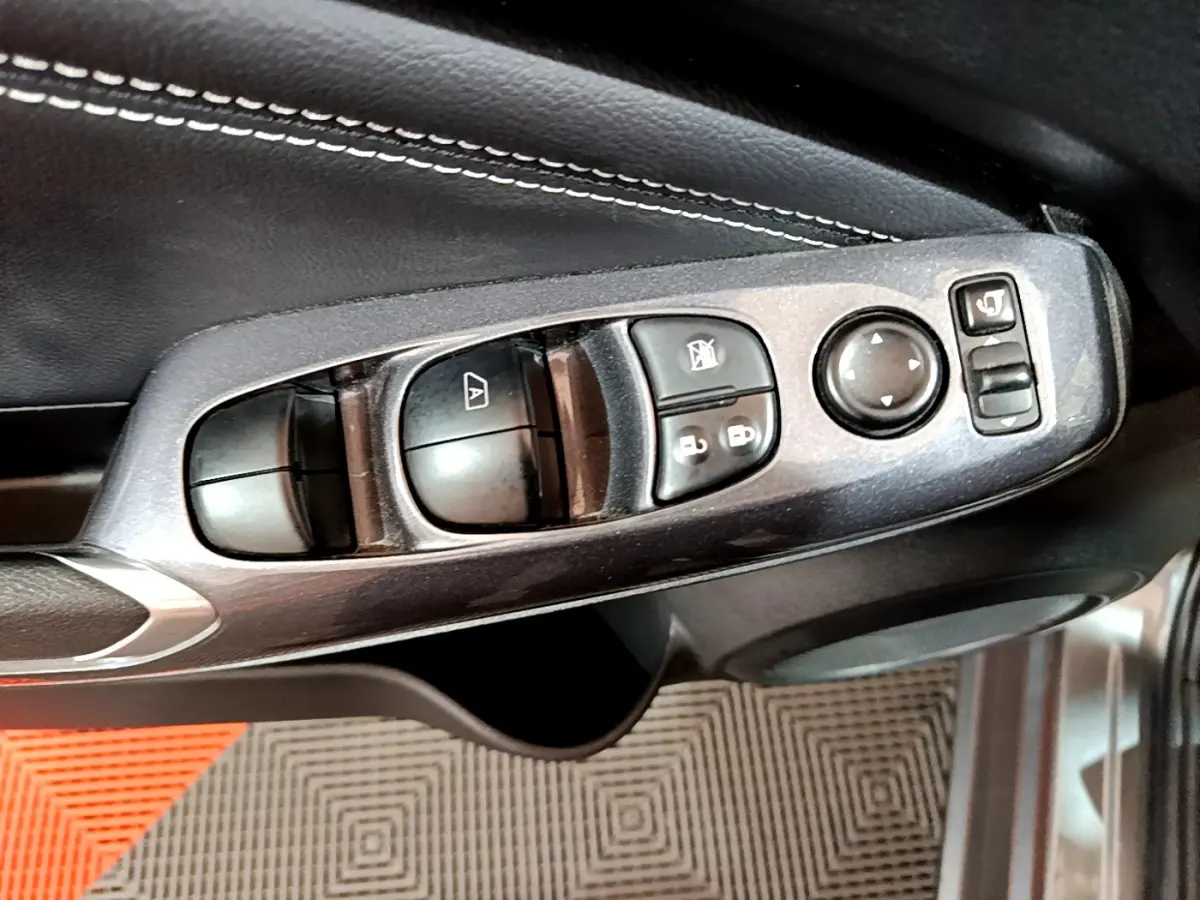 Commandes des vitres et rétroviseurs côté conducteur du Nissan Juke Hybrid 2023 gris foncé, intérieur en cuir noir.